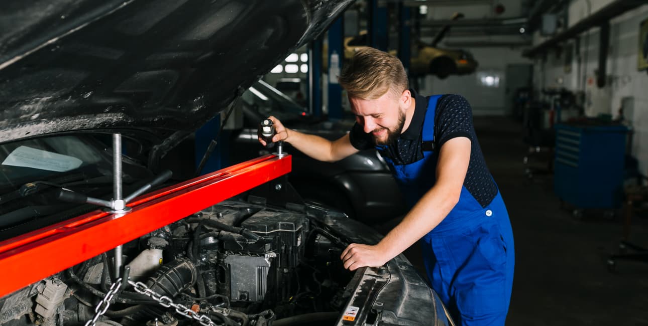 Mécanicien penché sur un moteur de voiture, capot ouvert